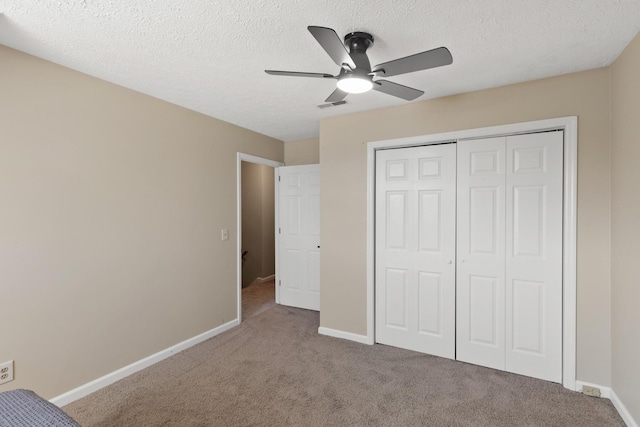 unfurnished bedroom with ceiling fan, a closet, a textured ceiling, and carpet flooring