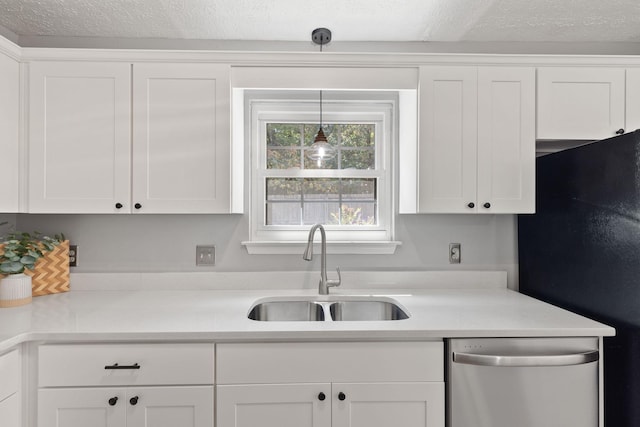 kitchen with pendant lighting, sink, dishwasher, white cabinets, and black fridge