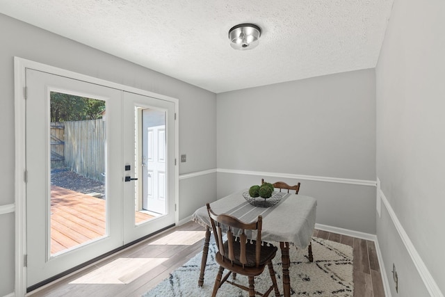 dining space featuring hardwood / wood-style floors, french doors, and a textured ceiling