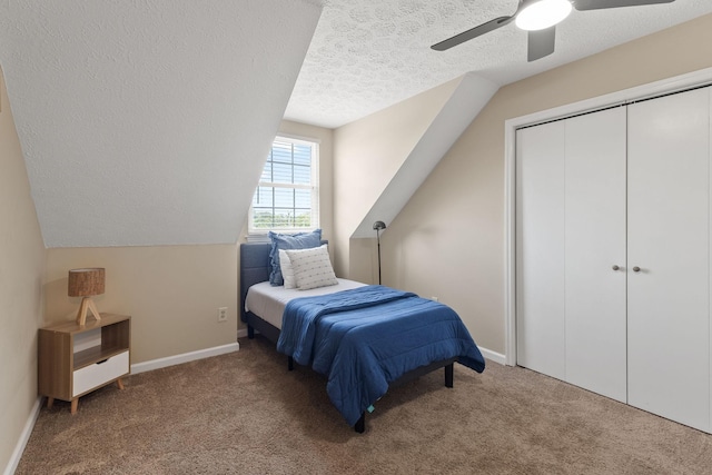 carpeted bedroom featuring ceiling fan, a closet, vaulted ceiling, and a textured ceiling