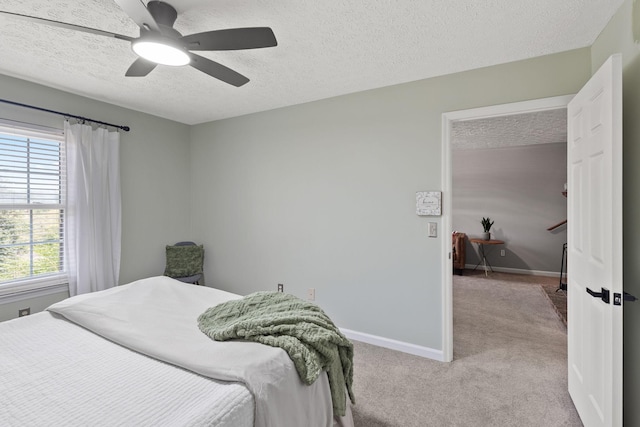 bedroom with ceiling fan, light colored carpet, and a textured ceiling