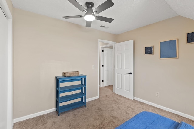 bedroom featuring vaulted ceiling, light colored carpet, a textured ceiling, and ceiling fan