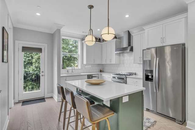 kitchen with a kitchen island, appliances with stainless steel finishes, white cabinetry, a kitchen bar, and wall chimney exhaust hood