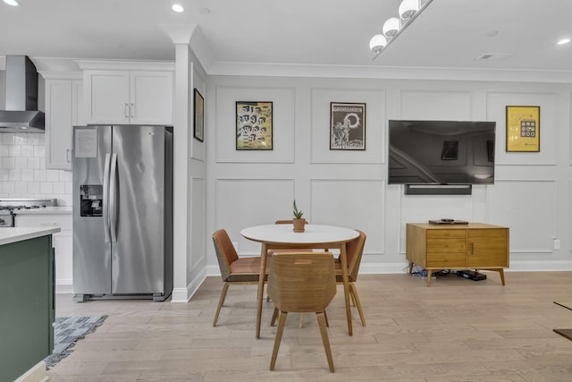 dining room with ornamental molding and light wood-type flooring