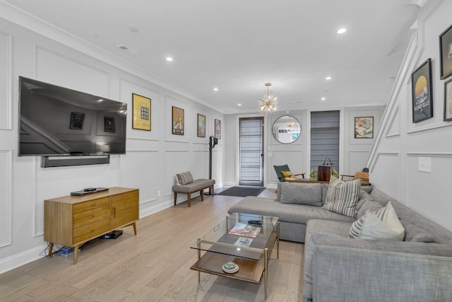 living room featuring ornamental molding, a chandelier, and light hardwood / wood-style flooring