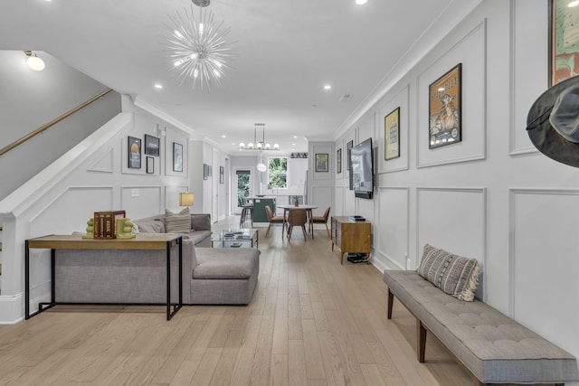 living room with ornamental molding, light hardwood / wood-style floors, and a notable chandelier