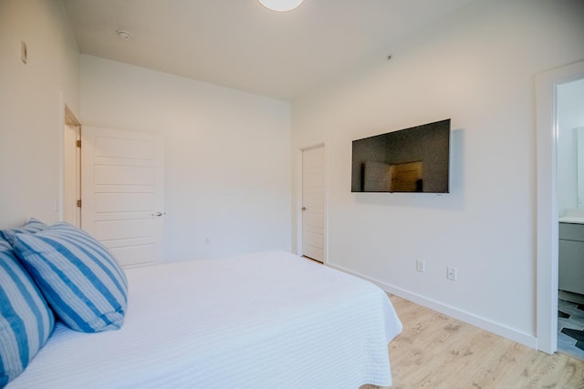 bedroom with connected bathroom and light hardwood / wood-style floors