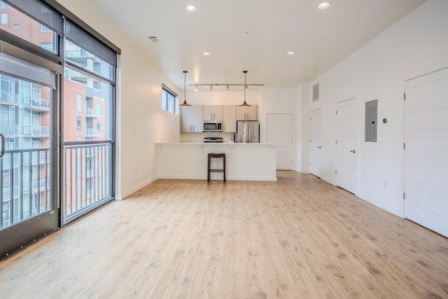 kitchen featuring appliances with stainless steel finishes, pendant lighting, electric panel, track lighting, and light wood-type flooring