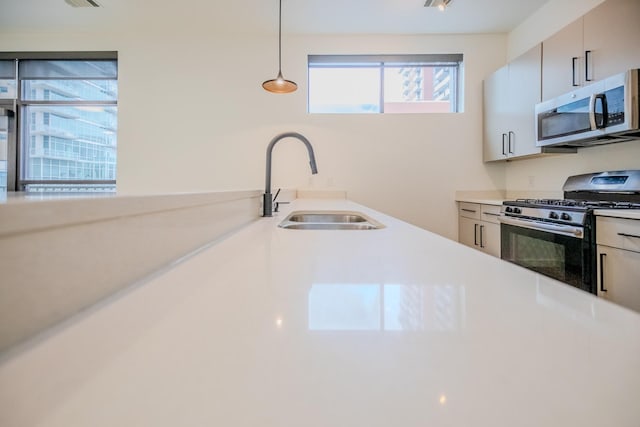 kitchen featuring appliances with stainless steel finishes, decorative light fixtures, and sink