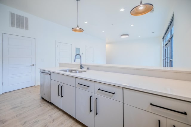 kitchen featuring sink, white cabinetry, light wood-type flooring, stainless steel dishwasher, and pendant lighting