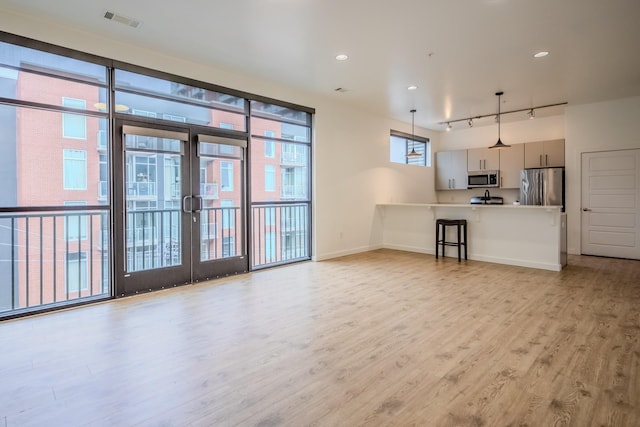 interior space with rail lighting, light hardwood / wood-style floors, and french doors