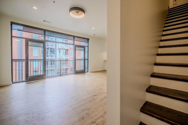 stairs featuring wood-type flooring and floor to ceiling windows