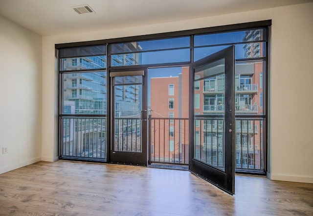 empty room featuring baseboards, visible vents, wood finished floors, and plenty of natural light