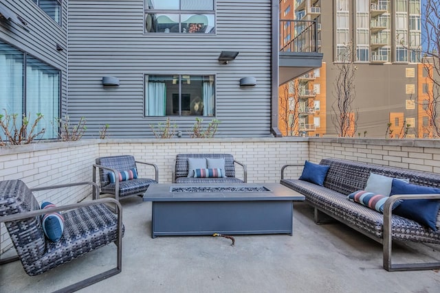 view of patio / terrace featuring a balcony and an outdoor living space with a fire pit