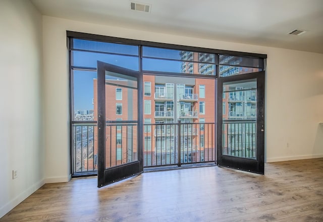 unfurnished room with baseboards, visible vents, and wood finished floors