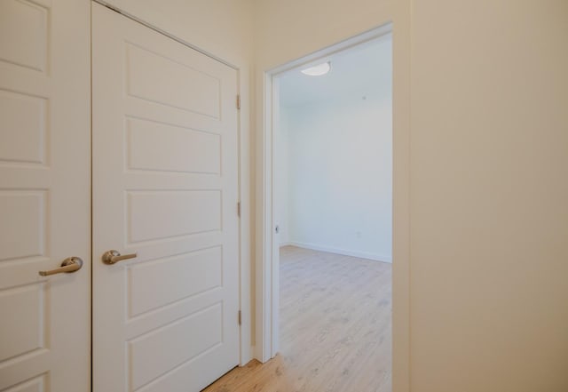 corridor featuring baseboards and light wood-style flooring