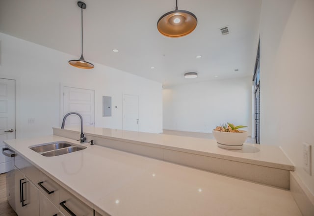 kitchen with light countertops, a sink, pendant lighting, visible vents, and white cabinets