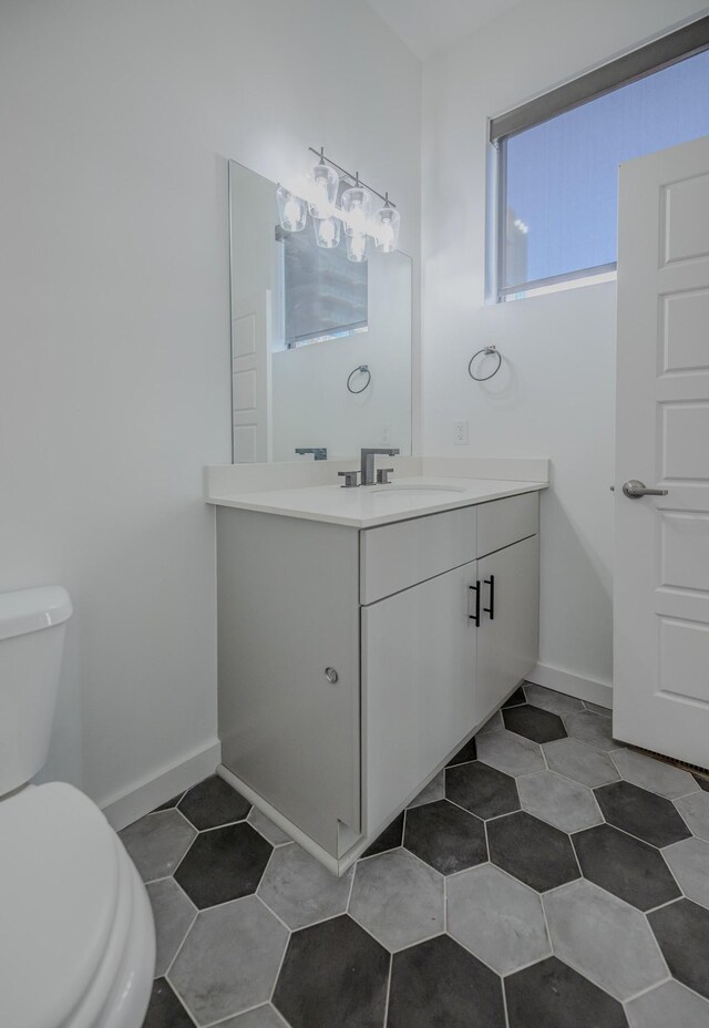 bathroom with toilet, vanity, tile patterned flooring, and baseboards