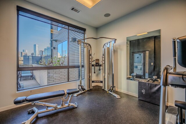 exercise area with baseboards, a view of city, and visible vents