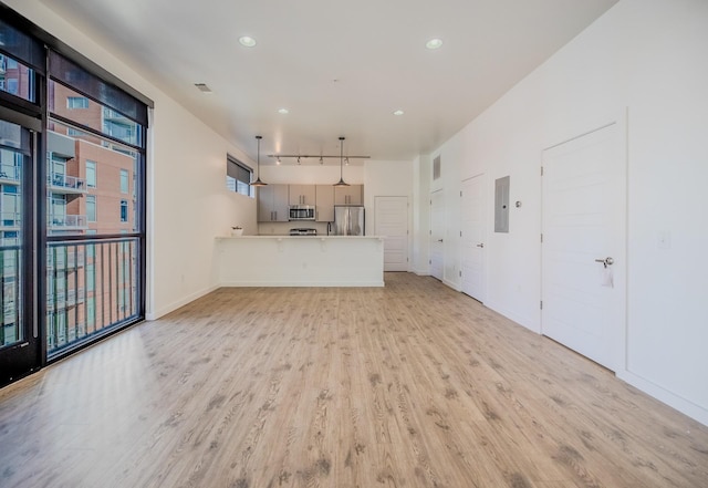 unfurnished living room with visible vents, baseboards, rail lighting, recessed lighting, and light wood-type flooring