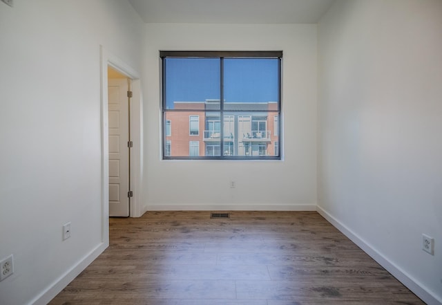 empty room featuring baseboards, visible vents, and wood finished floors