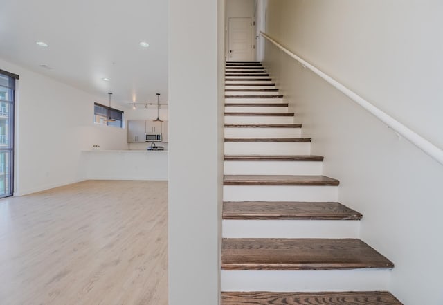 stairs featuring wood finished floors and recessed lighting