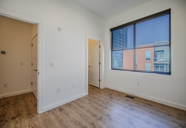 unfurnished bedroom with baseboards, visible vents, and wood finished floors