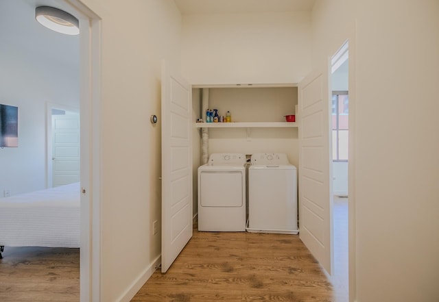 clothes washing area featuring light wood-style flooring, laundry area, and separate washer and dryer