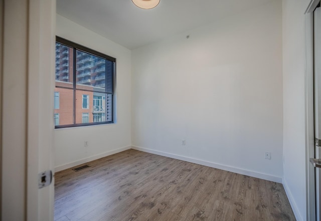 spare room featuring baseboards, visible vents, and wood finished floors