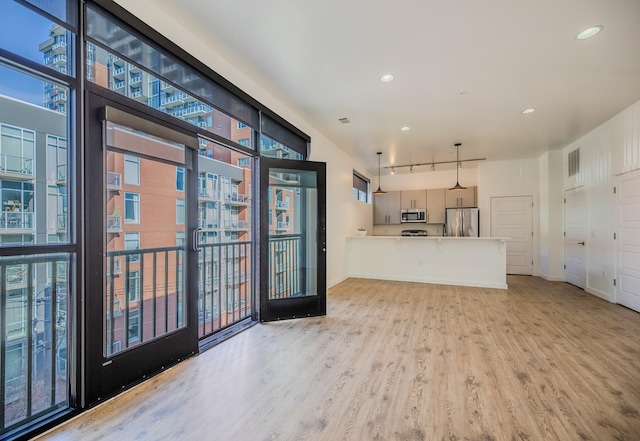 kitchen with recessed lighting, baseboards, a peninsula, appliances with stainless steel finishes, and wood finished floors