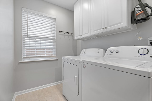 laundry area with cabinets, washing machine and clothes dryer, and light hardwood / wood-style flooring