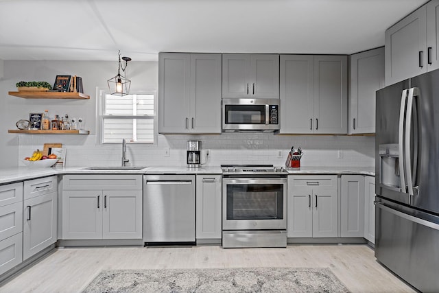 kitchen with sink, tasteful backsplash, light hardwood / wood-style flooring, gray cabinets, and stainless steel appliances