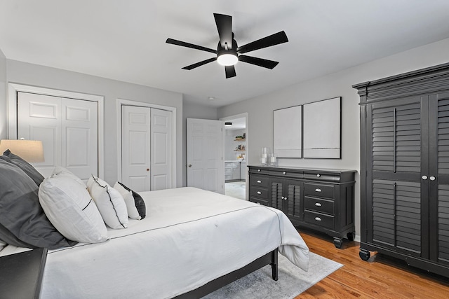 bedroom with multiple closets, ceiling fan, and light wood-type flooring