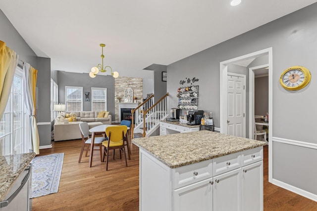 kitchen featuring light stone countertops, pendant lighting, white cabinets, and light wood-type flooring