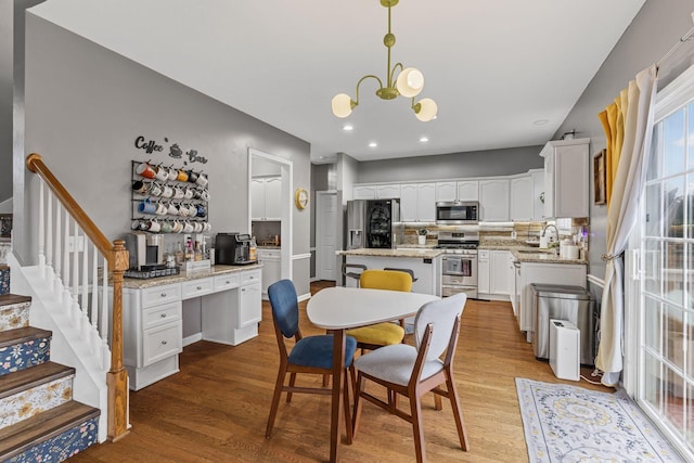 dining area with an inviting chandelier, sink, and light wood-type flooring