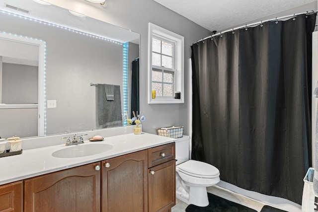 bathroom with tile patterned flooring, vanity, a textured ceiling, and toilet