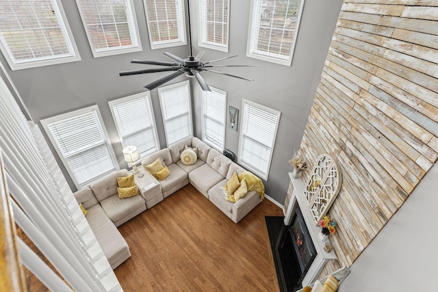 living room featuring a high ceiling, ceiling fan, and light hardwood / wood-style flooring