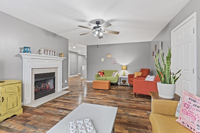 living room featuring dark hardwood / wood-style flooring, a tiled fireplace, a textured ceiling, and ceiling fan