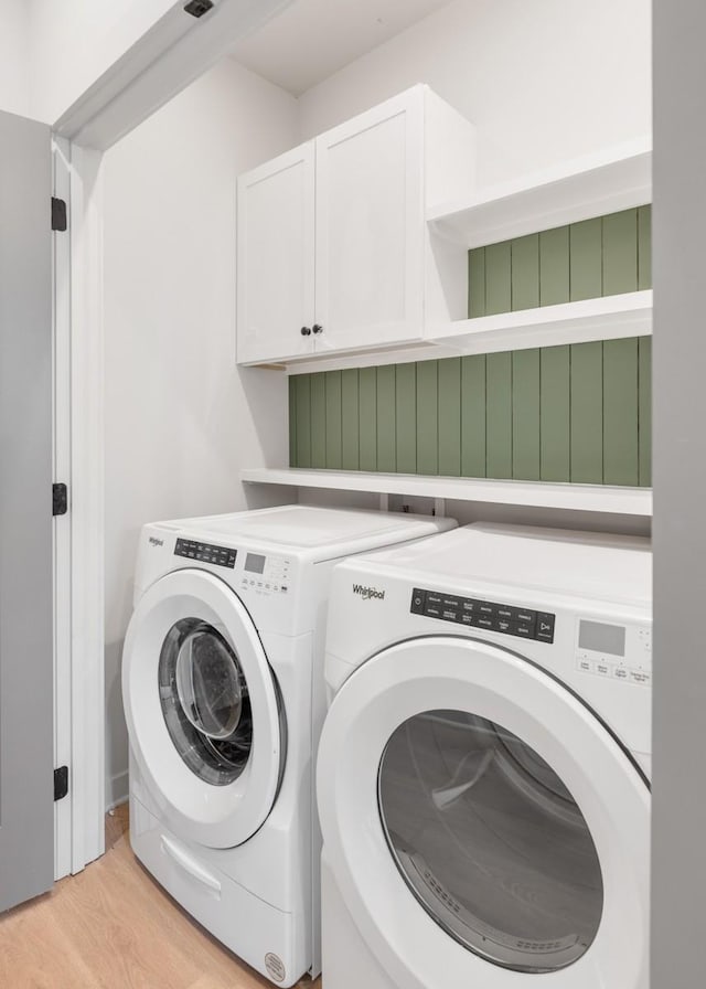 washroom with light wood-type flooring, separate washer and dryer, and cabinets