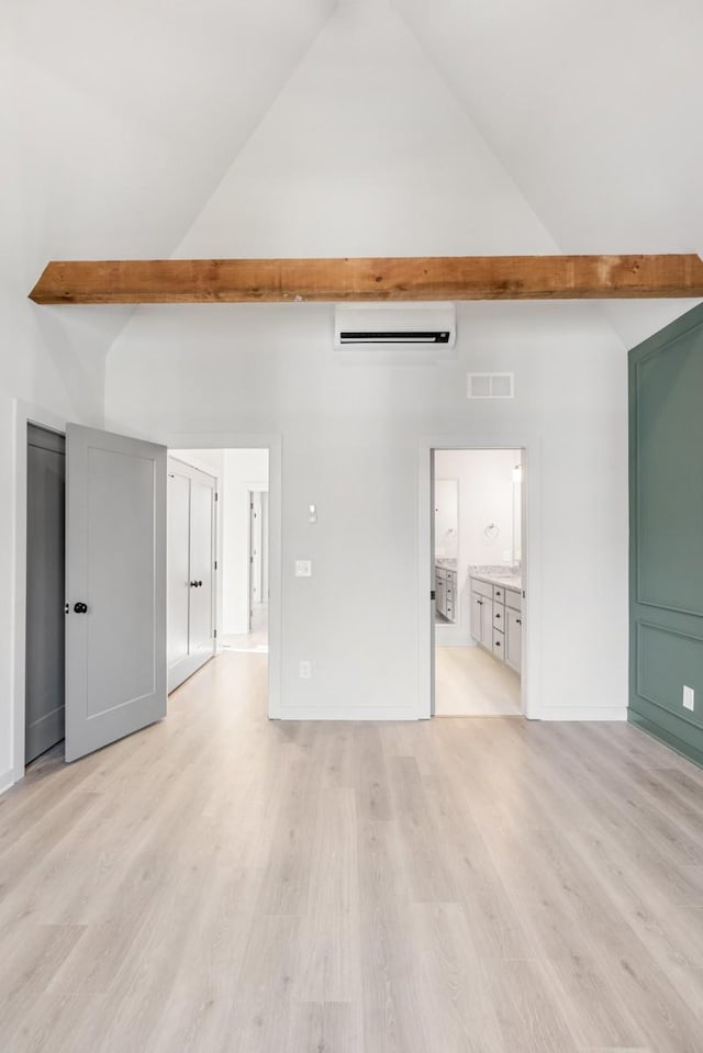 unfurnished living room featuring a wall mounted AC, high vaulted ceiling, light wood-type flooring, and beam ceiling