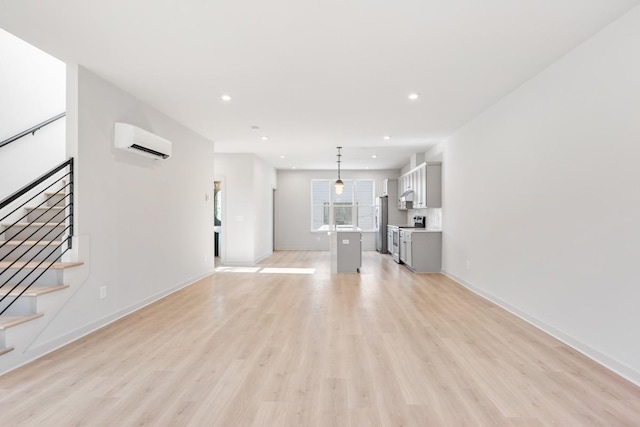 unfurnished living room featuring a wall mounted AC and light hardwood / wood-style flooring