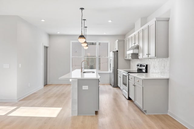 kitchen with sink, a kitchen island with sink, stainless steel appliances, light hardwood / wood-style floors, and decorative light fixtures