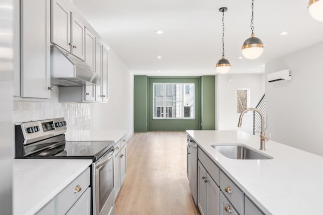 kitchen with appliances with stainless steel finishes, a wall mounted air conditioner, decorative light fixtures, sink, and backsplash