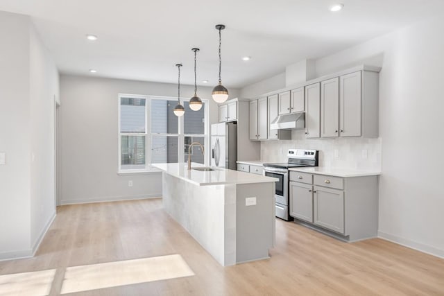 kitchen featuring sink, gray cabinets, pendant lighting, stainless steel appliances, and a kitchen island with sink