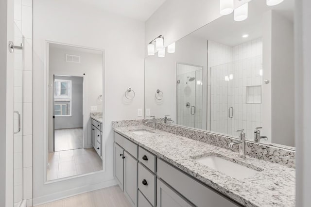 bathroom with vanity and a shower with door