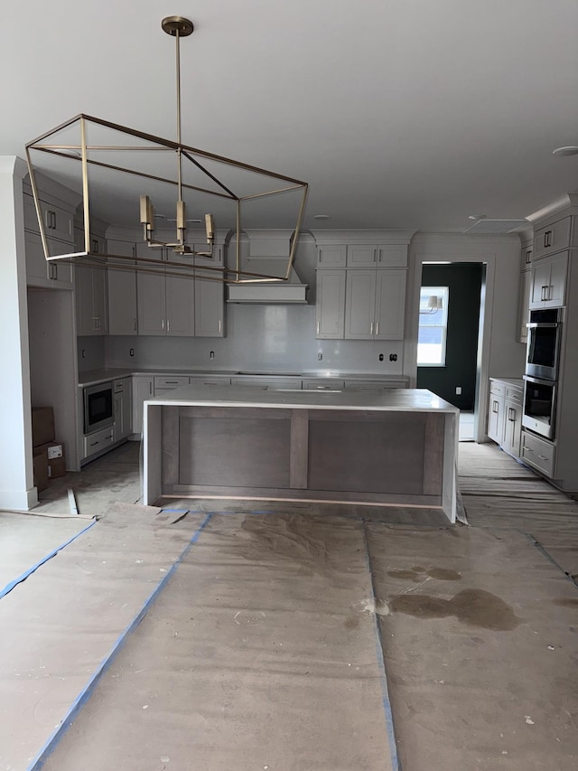 kitchen featuring a breakfast bar area, hanging light fixtures, gray cabinets, a kitchen island, and stainless steel appliances