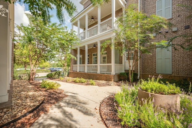 view of side of property with ceiling fan and a balcony