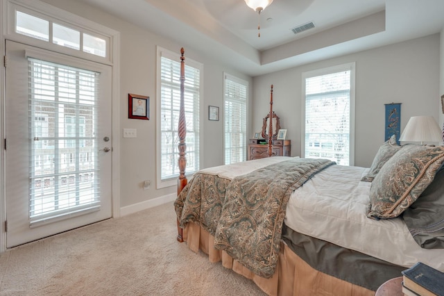 carpeted bedroom featuring ceiling fan, a raised ceiling, and access to outside