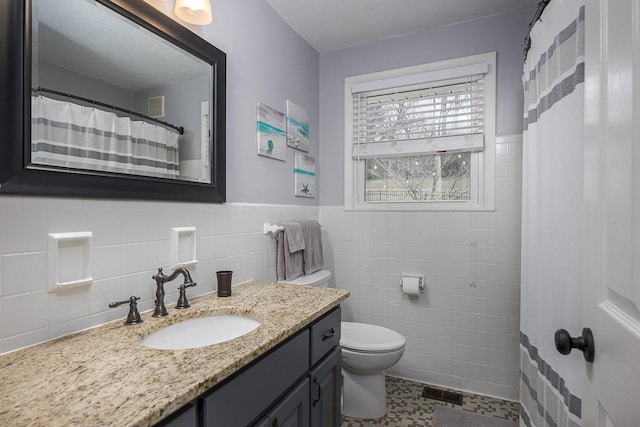 bathroom with vanity, tile walls, and toilet