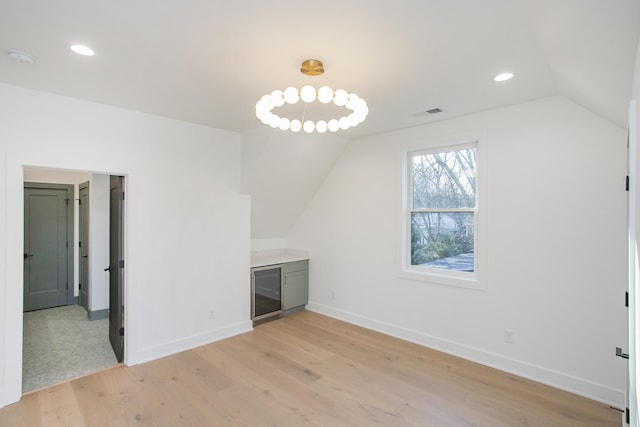 bonus room with beverage cooler, vaulted ceiling, and light hardwood / wood-style flooring